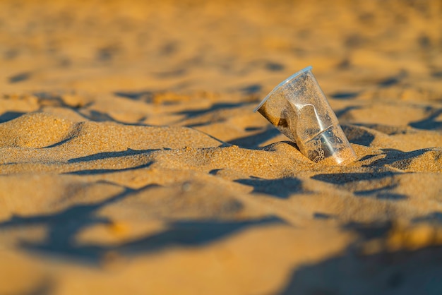 Rubbish Plastic cup on the golden beach sand of the ocean, playa de las Teresitas, Tenerife. Environment conservation concept. Seas ond oceans pollution with plastic waste. Recycle.