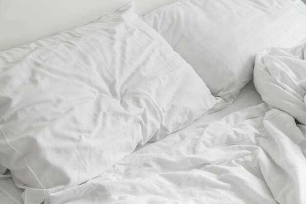 rumpled bed with white messy pillow decoration in bedroom