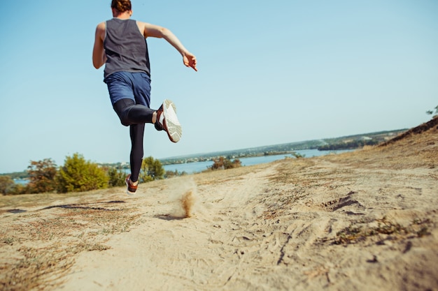 Running sport. Man runner sprinting outdoor in scenic nature. Fit muscular male athlete training trail running for marathon run.