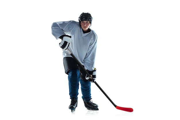 Running. Young male hockey player with the stick on ice court and white background. Sportsman wearing equipment and helmet practicing. Concept of sport, healthy lifestyle, motion, movement, action.