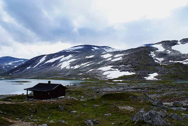 Free Photo rural norwegian cottage near lake surrounded by high rocky mountains at atlantic ocean road, norway