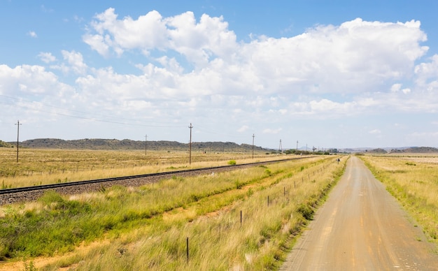 Free photo rural road next to a railway in a field