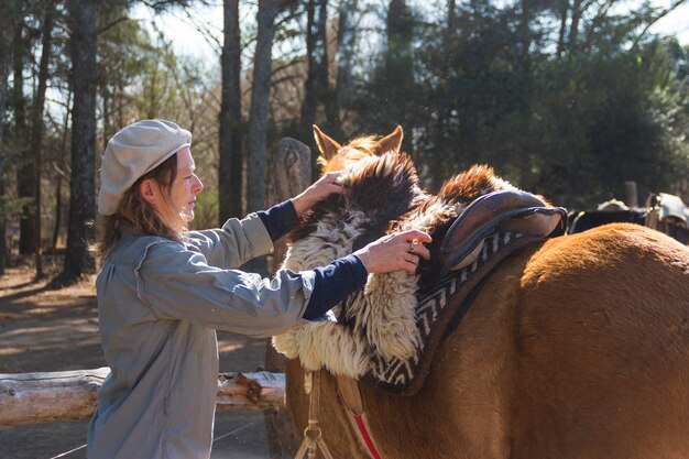 Rural woman saddling her horse in the field