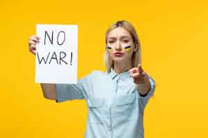 Free photo russian ukrainian conflict cute girl yellow background with ukrainian flag on cheeks no war