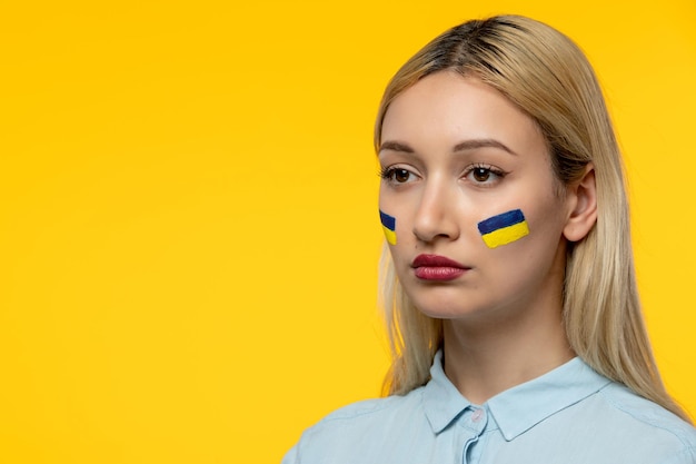 Russian ukrainian conflict young cute girl with ukrainian flag on cheeks close up face