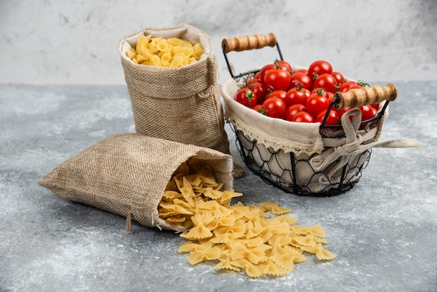 Rustic baskets of pasta with cherry tomatoes on a marble table.