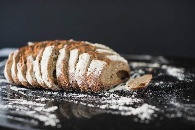 Rustic bread slices with dusted flour on reflective kitchen counter