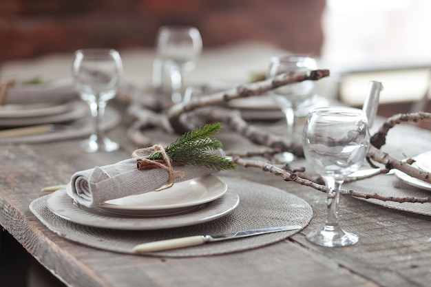 Free photo rustic christmas served wooden table with vintage silverware, candles and fir twigs.