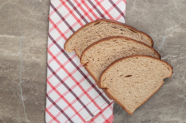 Rye bread slices and tablecloth on marble surface. High quality photo