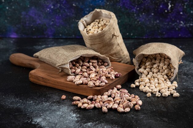 Sackcloth of dried raw beans placed on dark surface. .