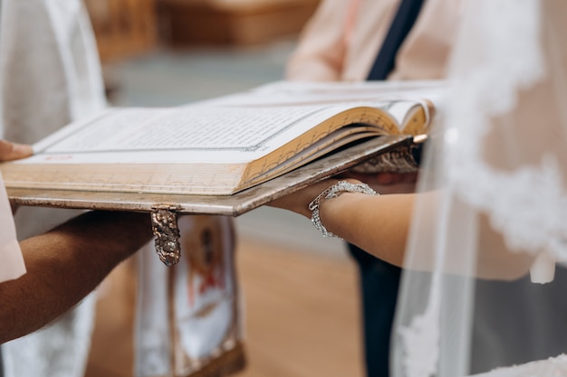 Sacred book of bible on the bride's hands on the sacramental wedding ritual in church