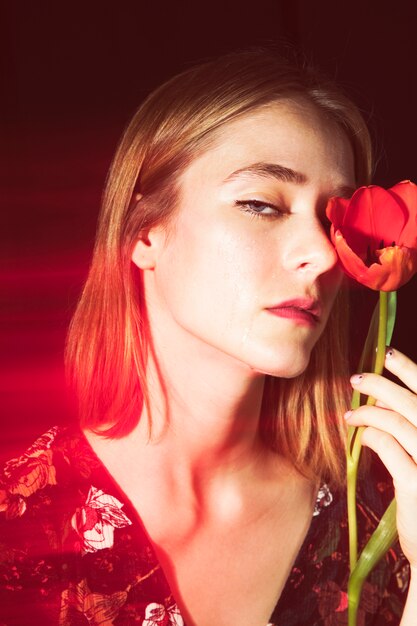 Sad blond woman with red tulip