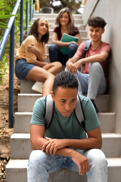 Free photo sad boy sitting on stairs front view