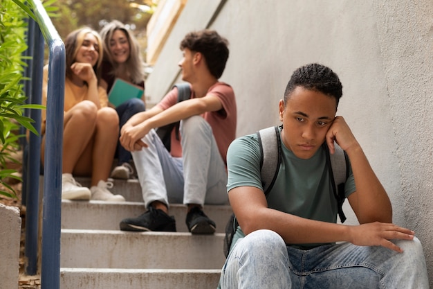 Sad boy sitting on stairs low angle