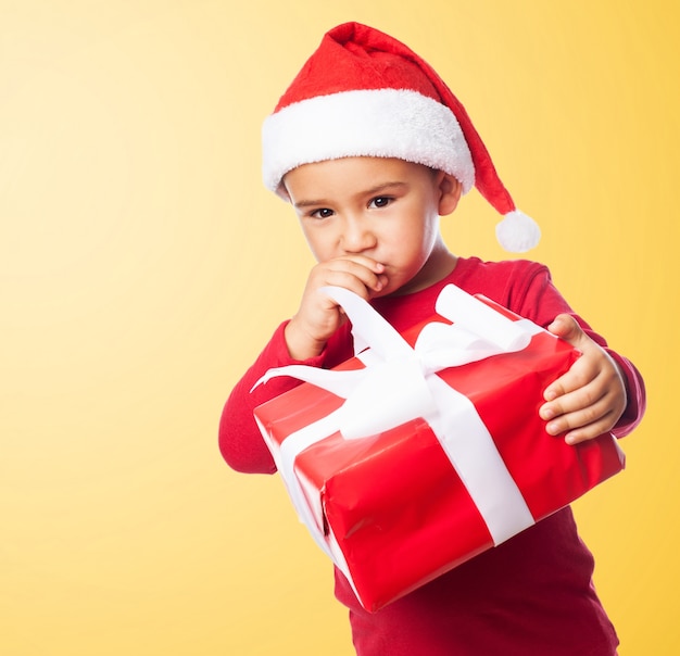 Sad child holding a gift with orange background