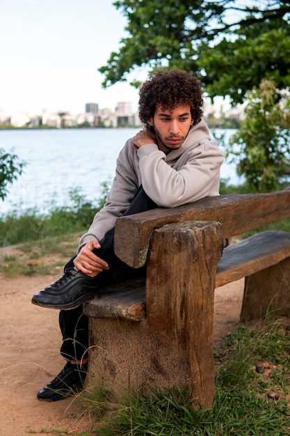 Free Photo sad and contemplative man sitting by the lake