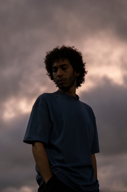 Free photo sad and contemplative man with clouds background