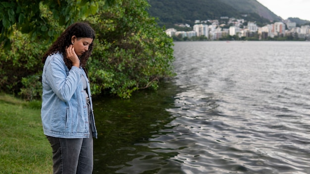 Free photo sad and contemplative woman sitting by the lake