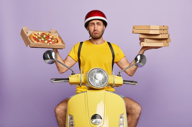 Free Photo sad deliveryman driving yellow scooter while holding pizza boxes