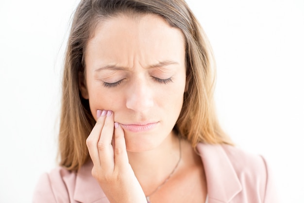 Sad face of young businesswoman having toothache