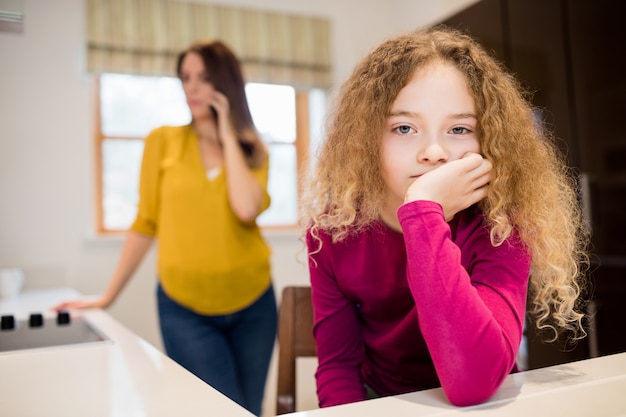 Sad girl sitting in kitchen