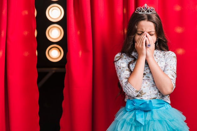 Free Photo sad girl standing behind the red curtain