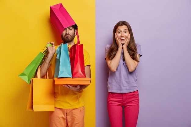 Free photo sad man overloaded with shopping bags, has wife shopaholic, spend free time during weekend on buying new clothes