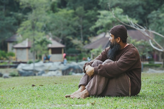 Sad man sitting on green grass