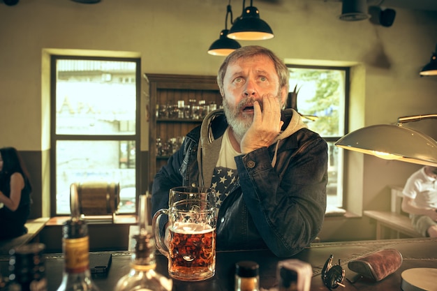 Free Photo the sad senior bearded male drinking beer in pub