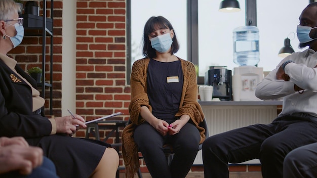 Sad woman crying at aa therapy meeting in front of group of people during covid 19 pandemic. Desperate person asking for help from psychiatrist at rehabilitation community program.