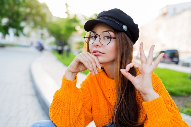 Sad woman showing ok ,  sitting on the street ,