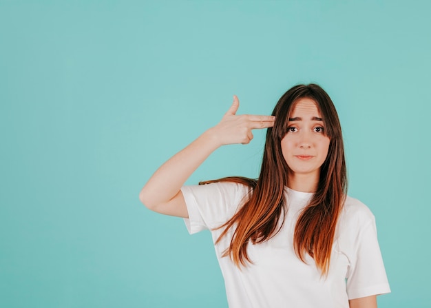 Sad woman with finger gun near head