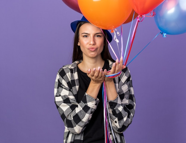 Sad young beautiful girl wearing party hat holding balloons 