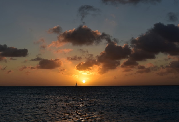 Free photo sailboat sailing in front of the setting sun in aruba.