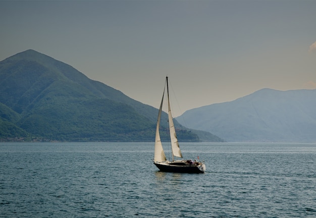 Sailing boat in the middle of the calm sea by the hills captured in Switzerland