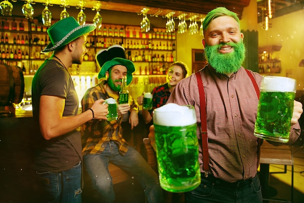 Free photo saint patrick's day party. happy friends are celebrating and drinking green beer.