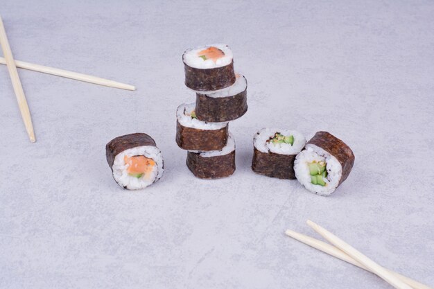 Sake maki rolls on grey background with chopsticks