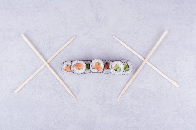 Sake maki rolls with salmon and avocado on grey.