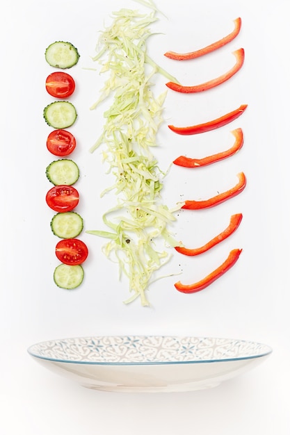 Free photo salad bowl with falling vegetables