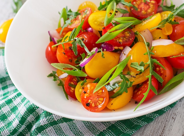 Salad of fresh cherry tomatoes with onion and arugula