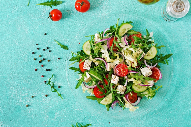 Salad of fresh vegetables - tomato, cucumber and feta cheese in Greek style. Flat lay. Top view