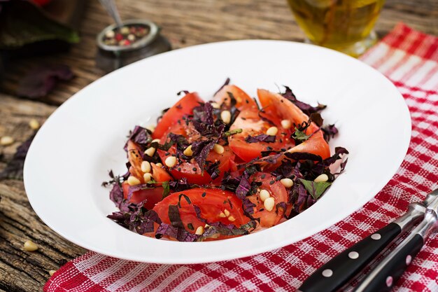 Salad from tomatoes with a violet basil and pine nuts. Vegan food. Italian meal.