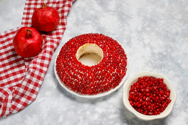 Salad Garnet bracelet. Vegetable salad with pomegranate seeds with pomegranate on concrete 