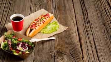 Free photo salad and hot dogs on wooden background