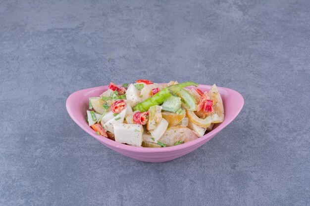 Salad with chopped vegetables and herbs on blue surface