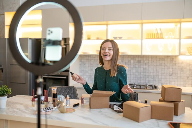 Sale. Young woman in green dress conducting online cosmetic sale