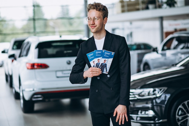 Salesman at a car showroom with business flyers