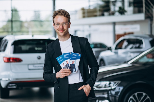 Salesman at a car showroom with business flyers