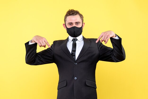 Salesman pointing down with his thumbs on isolated yellow