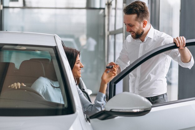 Salesman and woman looking for a car in a car showroom